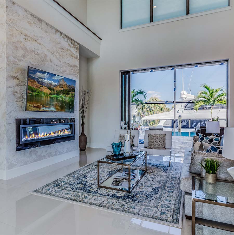 Luxury custom home build featuring large living room with fire place and stone work and marble floors and water views